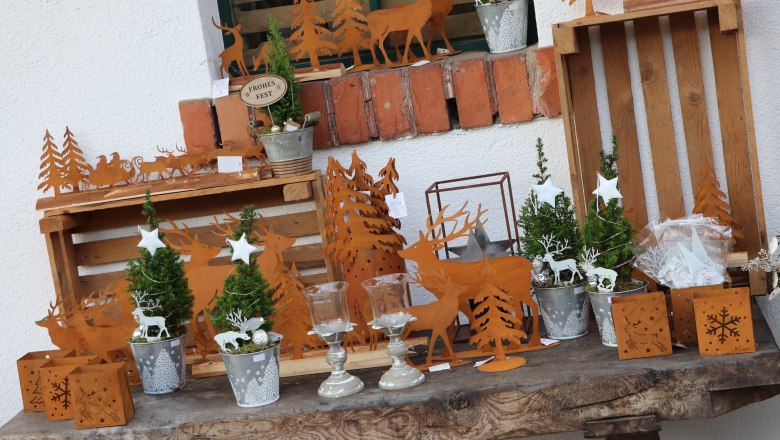 Beerenhof Prenner, © Trixi Rollin Weihnachtliche Dekoration mit Rentier- und Tannenbaum-Motiven aus Metall auf einem Holztisch.