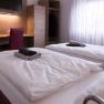 Double room, © W. Garhöfer Twin room with two beds, desk, chair and closet. Towels on the beds, window with curtains in the background.