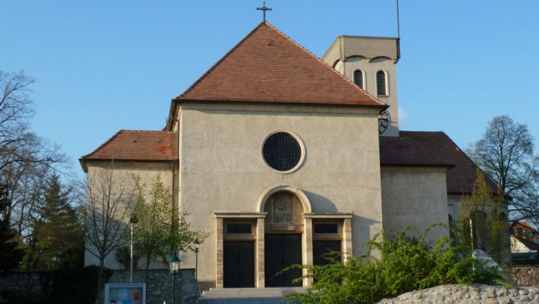 Kirche, © Werner Ertl Frontansicht einer Kirche mit rotem Dach und rundem Fenster.