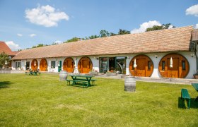 Winzerhof Küssler, © Winzerhof Küssler Ein Winzerhof mit runden Holztüren und grüner Wiese im Vordergrund.