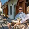 Winery Küssler, © Winzerhof Küssler A man and a woman are sitting at an outdoor table in front of a building with wooden doors.