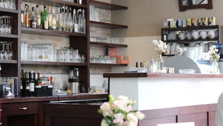 Schank im Weydner Wirtshaus, © Weydner Wirtshaus Innenansicht einer Bar mit Regalen voller Gläser und Flaschen, Blumen auf dem Tresen.