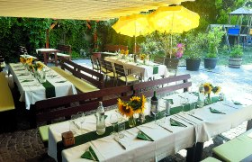 Heurigenlokal Storch, © Schönner Gedeckte Tische im Freien mit Sonnenblumen und gelben Sonnenschirmen.