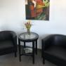 Amber Motel, © Bernstein Motel Two black armchairs and a round table with flowers in a room. An abstract painting with a fox motif hangs on the wall.