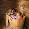 Winery Küssler, © Winzerhof Küssler A couple relaxes in a wooden hot tub with wine in a rustic room.