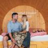 Wine barrel suite, © Winzerhof Küssler A couple is sitting in a large wooden wine barrel that has been converted into a suite.