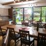 Winery Küssler, © Winzerhof Küssler Interior view of a modern dining room with wooden tables and chairs, large windows and a view of a garden.