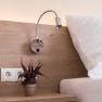 Double room, © W. Garhöfer Close-up of a bed with wooden back panel, reading lamp, sockets and potted plant.