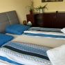 Schlafzimmer, © Dana Perl Ein gemütliches Schlafzimmer mit einem Doppelbett, blauer Bettwäsche und gefalteten Handtüchern. Im Hintergrund ein Schrank mit Pflanzen.