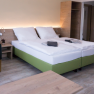 Family room, © W. Garhöfer Modern furnished hotel room with double bed, bedside table, armchair and closet.