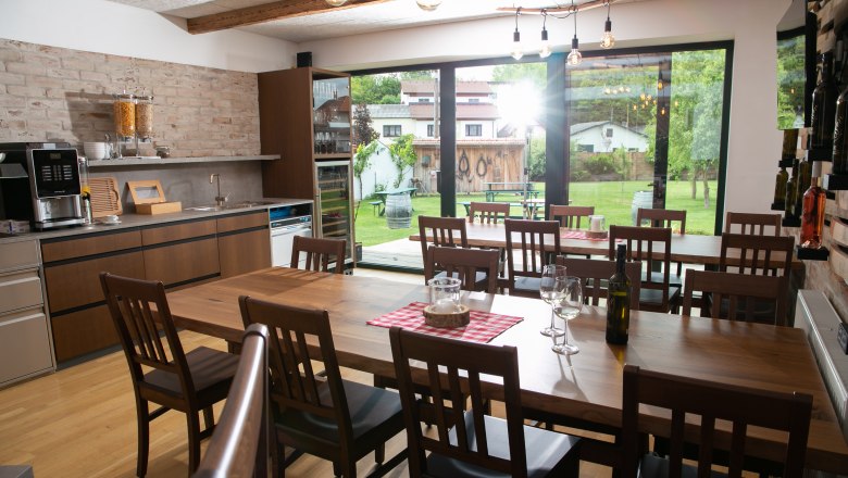 Winzerhof Küssler, © Winzerhof Küssler Esszimmer mit Holztisch, Stühlen und Blick auf den Garten durch große Fenster.