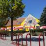 Garden, © © GH Prinz Eugen A yellow building with murals, surrounded by trees and red parasols.