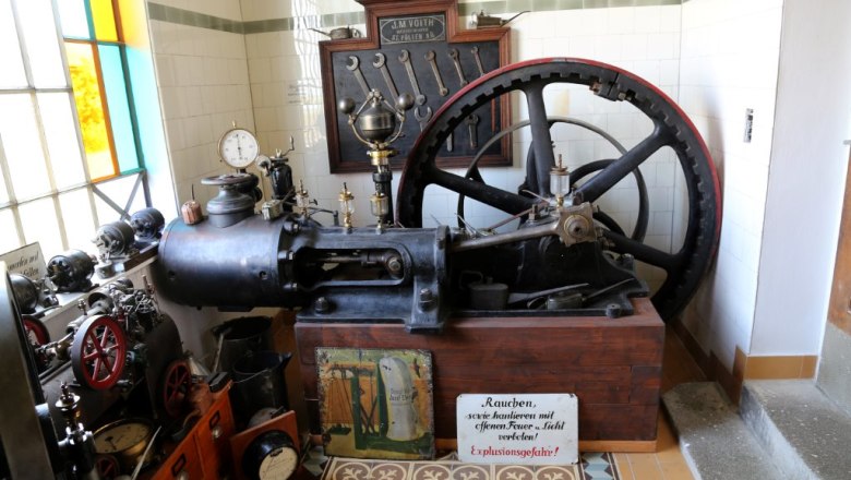 Old steam engine in the museum with tools and warning sign.