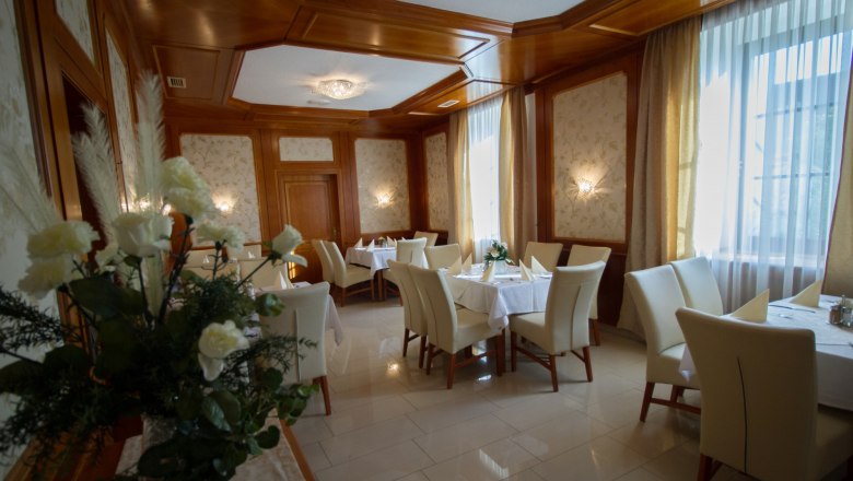 Elegant dining room with laid tables, white chairs and flower arrangements.