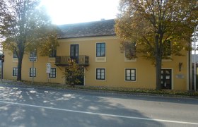 Gelbes Gebäude mit Balkon und Bäumen davor, Erzherzog Carl Haus und Napoleonmuseum in Deutsch-Wagram.