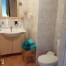Ein Badezimmer mit Waschbecken, Spiegel, Toilette und Handtüchern auf einem Hocker.
