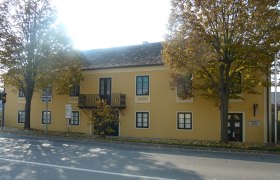 Gelbes Gebäude mit Balkon und Bäumen davor, Erzherzog Carl Haus und Napoleonmuseum in Deutsch-Wagram.