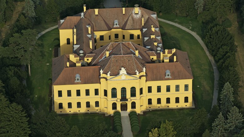 Aerial view of Eckartsau Castle, surrounded by trees and gardens.