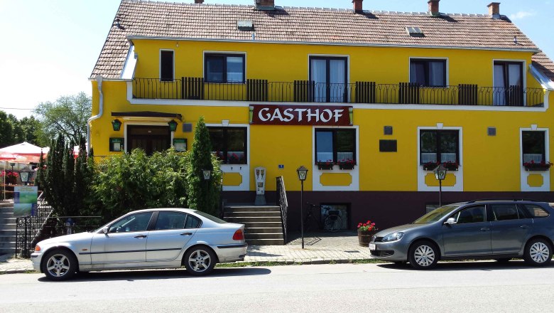 Gelbes Geb&auml;ude mit der Aufschrift 'Gasthof', zwei geparkte Autos davor.