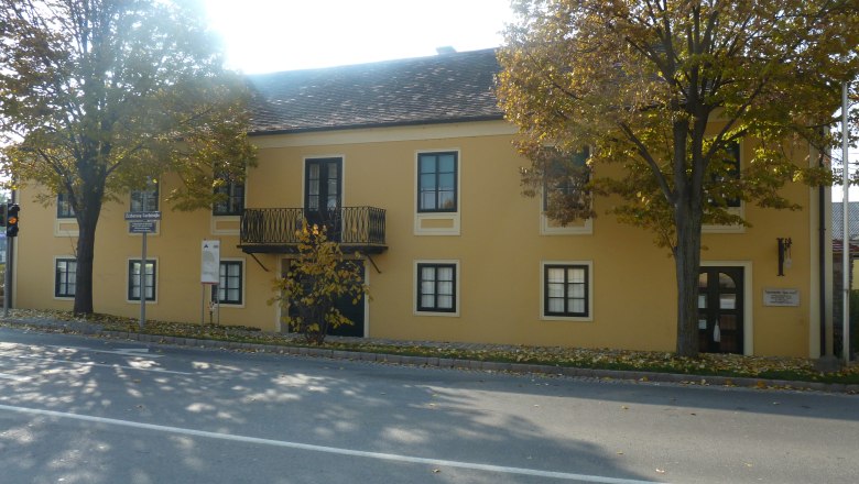 Yellow building with balcony and trees in front, Archduke Carl House and Napoleon Museum in Deutsch-Wagram.
