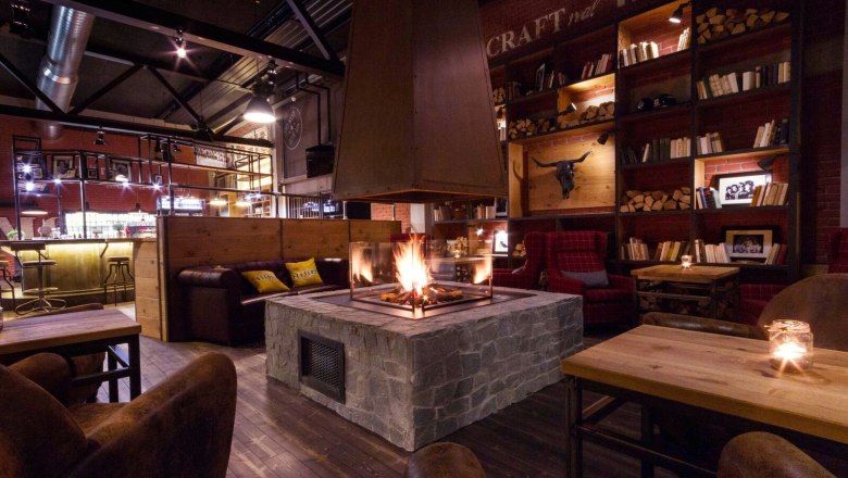 Gemütlicher Raum mit Kamin, Holzmöbeln und Bücherregalen.