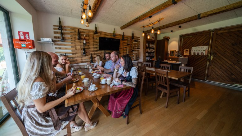 Group of people in traditional dress sitting at a table in a rustic room.