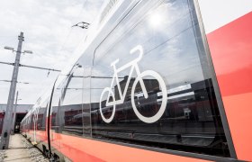 Ein moderner Zug mit einem Fahrradsymbol auf dem Fenster, das anzeigt, dass Fahrr&auml;der erlaubt sind.